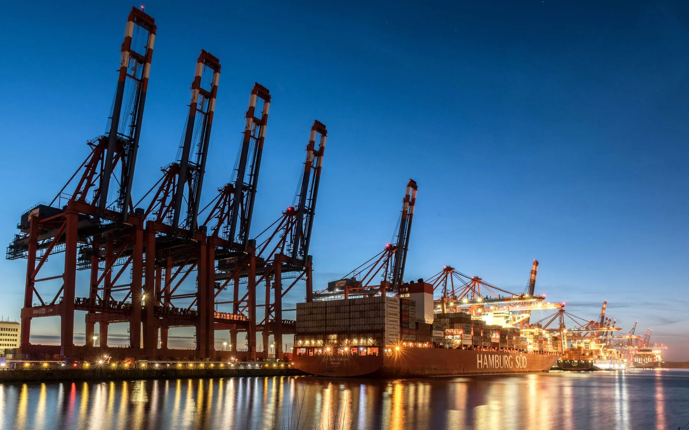 Container cranes and a ship at a harbour at dusk
